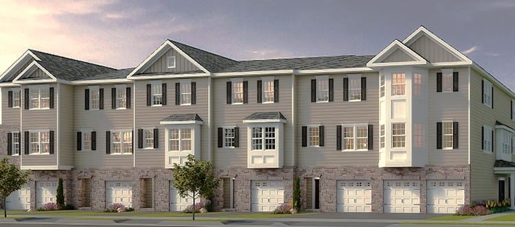 Row of modern townhomes in Middletown with gray siding, black shutters, stone garage bases, and bay windows at dusk