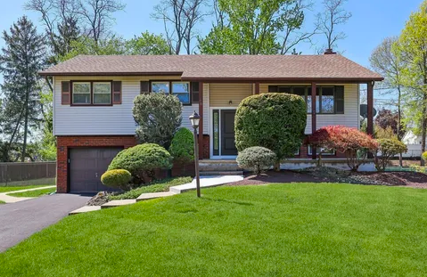 Split‑level suburban house in Manalapan with landscaped front yard and porch