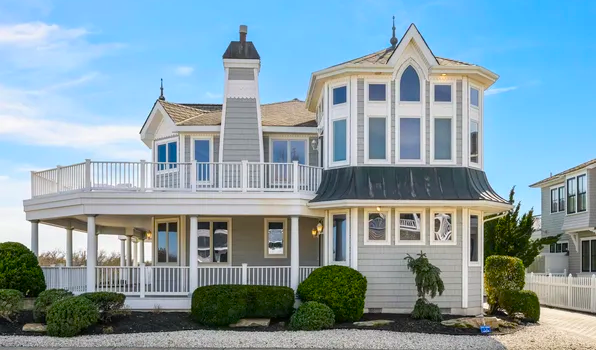 Victorian Cape May house with ornate trim, wraparound porch, and coastal gardens