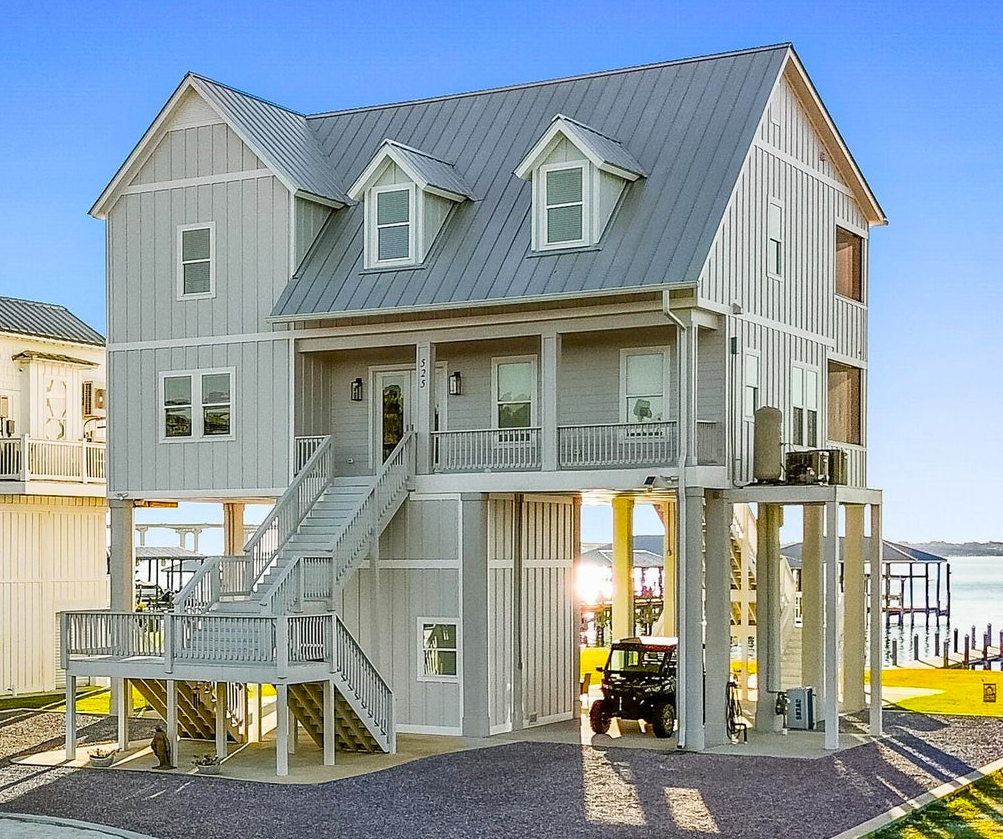 Elevated coastal bungalow with storm shutters and ocean‑facing porch